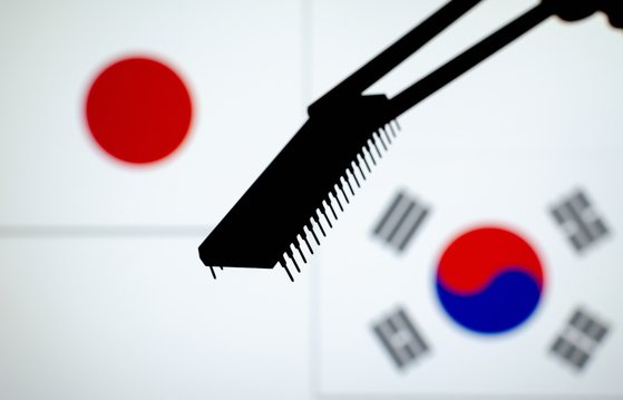 半導体チップの裏で韓国と日本の国旗が相対している。日本が半導体ドリームチームを稼動すれば韓日間の貿易戦争が激化することになる。［シャッターストック］