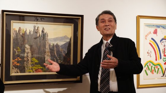 ５５年間に約１万２０００点の絵を韓日両国に寄贈した在日韓国人２世、河正雄（ハ・ジョンウン）氏。ホ・フン氏の金剛山（クムガンサン）の前で「在日」画家の絵を説明している。　［写真　在日韓国文化院］
