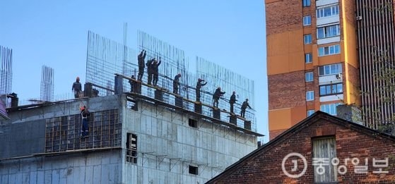 北朝鮮人労働者が先月末にロシア沿海州ウラジオストク都心部にある大型工事現場の高層部で鉄筋で建物の骨組みを作る工事を進めている様子。［写真　カン・ドンワン東亜大学教授］