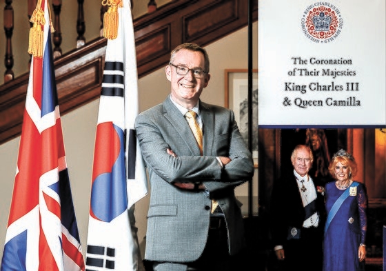 ９日、中央日報のインタビューに応じ、太極旗とユニオンジャック（英国国旗）、チャールズ３世夫妻の写真の前でポーズをとるコリン・クルックス駐韓英国大使。今年は韓英修交１４０周年。　キム・ギョンロク記者