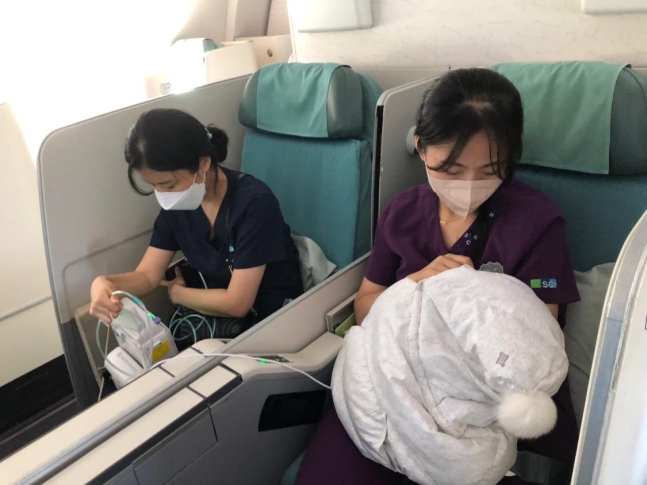 韓国に搬送する飛行機の中で未熟児の女児の世話をする順天郷大学富川病院の医療スタッフ。［写真　順天郷大学富川病院］
