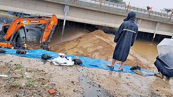 １５日午前８時、美湖江（ミホガン）の堤防一部が決壊する４０分前に川の水が上昇する中で作業員が忠清北道清州五松邑（チュンチョンブクド・チョンジュ・オソンウプ）の宮坪（クンピョン）２地下車道の近くで掘削機を動員して土で美湖江臨時堤防を積んでいる。