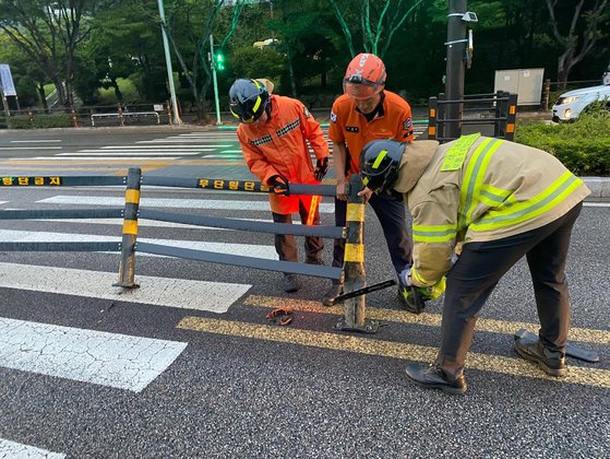 台風６号の影響圏に入った釜山で９日午後、道路に設置された鉄製の中央分離帯が破損し、消防隊員らが措置を取っている。［写真　釜山消防災難安全本部］