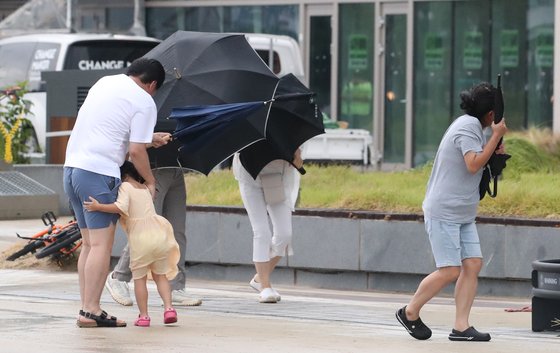 台風６号「ＫＨＡＮＵＮ（カーヌン）」の影響で９日に強風が吹いた釜山市海雲台区（プサンシ・ヘウンデグ）で、市民が傘を握りしめながら辛うじて歩いている。韓国気象庁は今日（１０日）、台風６号が南海岸に上陸すると予想している。ソン・ボングン記者