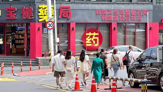 済州市蓮洞（チェジュシ・ヨンドン）のある免税店の駐車場の中に中国人観光客が移動している。駐車場前には中国語の看板がかかった薬局が営業している。チェ・チュンイル記者