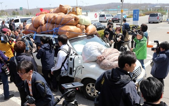 ２０１３年４月、乗用車に物品を積み込んで韓国側に入ってくる開城工業団地関係者を取材陣が囲む姿。［中央フォト］