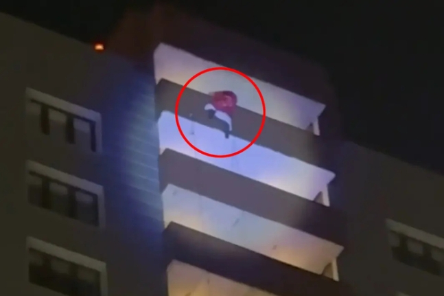 ロシア式サンタクロースの衣装を着て建物に登った男性。［写真　ＳＮＳキャプチャー／ニューヨーク・ポスト　キャプチャー］