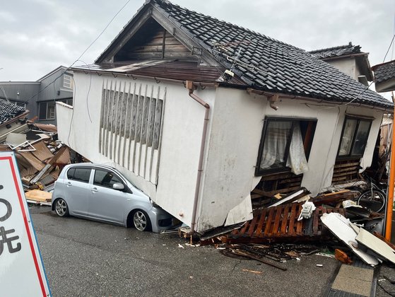 ３日、石川県輪島市の住宅街で車が崩壊した建物の下敷きになっている。キム・ヒョンイェ特派員