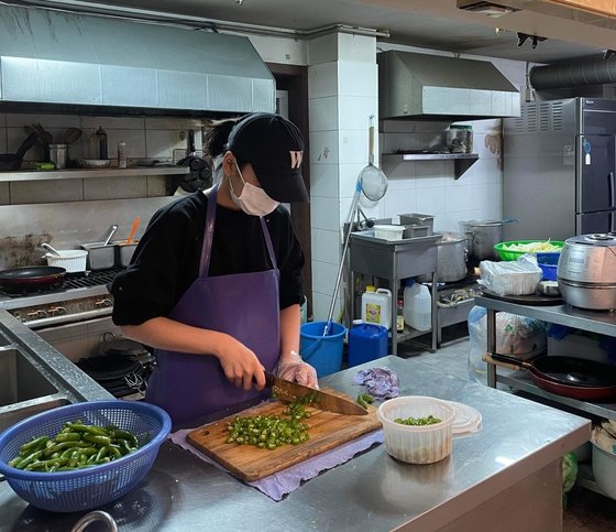 平沢大学映画科３年生のベトナム出身の留学生レティティさん（２３）が、学校近くの食堂で唐辛子を切っている様子。ソン・ソンベ記者