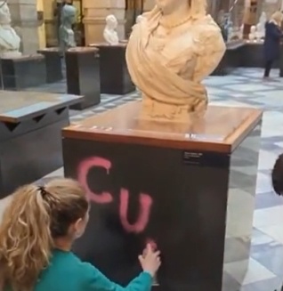 英国で環境活動家が英女王象にスプレーを吹きかけて文字を描いている。［Ｘ　キャプチャー］