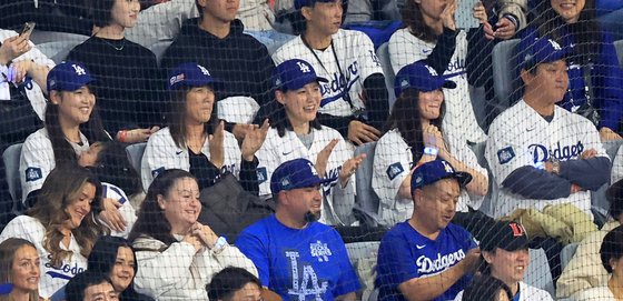 ドジャースのユニフォームと帽子を着用して夫を応援する大谷の妻。［写真　ニュース１］