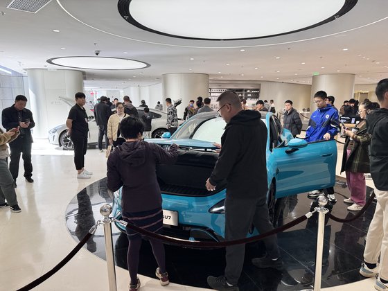 ３１日、北京王府井ショッピングモール「東方新天地」のシャオミ店舗に展示されているシャオミ電気自動車ＳＵ７。休日には家族連れの客が目立った。　シン・ギョンジン記者