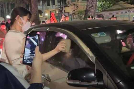 ベトナム・ハノイの路上で夫が車に不倫相手を乗せたと疑った妻が車窓をレンガで叩き割る様子。［写真　ＳＮＳキャプチャー］
