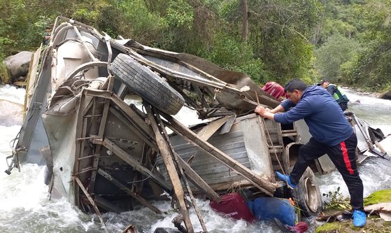 渓谷の下の川に転落したバスの残骸を調べる警察。［写真　ＡＦＰ＝聯合ニュース］