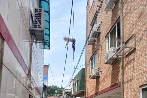 高さ６メートルの電線に引っかかっている外国人女性。［写真　ニューシス］