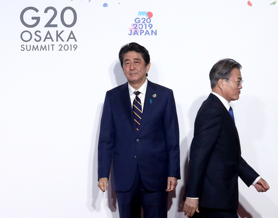 文在寅前大統領（右）が２０１９年６月２８日に大阪で開かれたＧ２０首脳会議公式歓迎式で議長国の安倍晋三首相（当時）と握手した後席に移動している。［中央フォト］