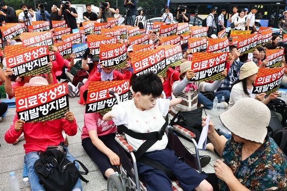 先天性希少疾患である「コルネリア・デランゲ症候群」を患っているパク・ハウンさん（中央）と母親が４日、ソウル鍾路区（チョンノグ）の普信閣の前で患者団体が主催した医師集団休診撤回集会に参加している。キム・ジョンホ記者
