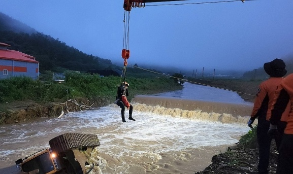 南海岸に大雨が降った１６日午前、全羅南道珍島郡古郡面金渓里（クムゲリ）の河川に掘削機が落下し、消防隊員が行方不明者がいないか周辺を捜索している。［写真　全羅南道消防本部］  ​