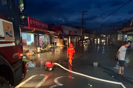 韓国南海岸に１時間当たり１００ミリを越える大雨が降った１６日、浸水した全羅南道海南郡（チョルラナムド・ヘナムグン）の山亭（サンテイ）市場で消防隊員が排水作業を行っている。［写真　全南消防本部］