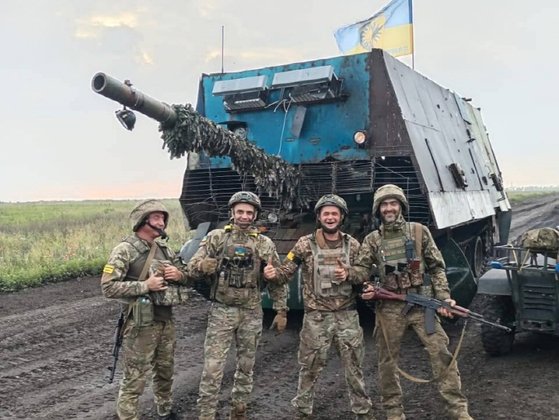 ロシア軍から奪った亀戦車の前で写真撮影をするウクライナ兵士。粗雑な形態から急造装備ということが分かる。　［写真　ウクライナ国防部］