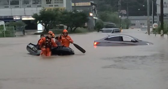 京畿北部地域に豪雨特報が下された１８日、京畿道坡州市月籠面のある道路が冠水し、消防隊員が孤立した市民を救助している。［写真　京畿北部消防災難本部］