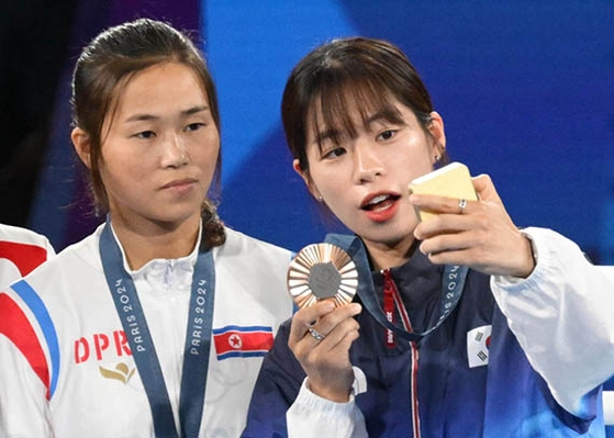 パリ五輪ボクシング女子５４キロ級で銅メダルを獲得した林エジ（イム・エジ）が北朝鮮のパン・チョルミ（右）と表彰台でサムスン電子のギャラクシーＺフリップ６で記念撮影をしている。　キム・ソンリョン記者