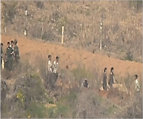 韓国国防部は北朝鮮軍が猛暑と梅雨で劣悪な環境の中でも毎日１３時間ずつ戦線地域に兵力を送り、地雷埋設、不毛地造成、防壁設置など「南北断絶」作業を数カ月にわたり続けている状況がとらえられたと１７日に明らかにした。写真は戦線地域の作業人材が不足し女性兵も投入された様子。［写真　韓国国防部］