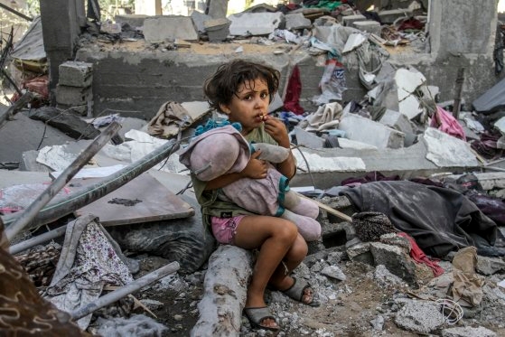 写真＝イスラエルの空襲で倒壊した家のがれきに座っている子ども［新華社通信＝聯合ニュース］