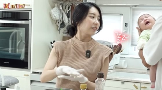 台所で料理するアヤネさんと生後２カ月の赤ちゃん。［写真　ユーチューブ（ＹｏｕＴｕｂｅ）チャンネル「ジアライフ」　キャプチャー］