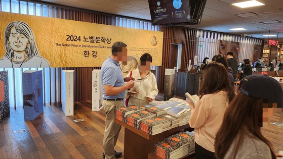 １４日午後６時ごろ、教保（キョボ）文庫光化門（クァンファムン）店に用意された韓江（ハン・ガン）氏の本が平積みされた特別カウンターの前で市民が本を読んでいる。［写真　キム・ソウォン記者］