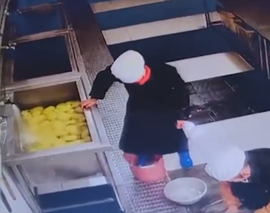 長靴で食材料を踏んでいる中国中学校給食室職員。［写真　ＳＮＳ］