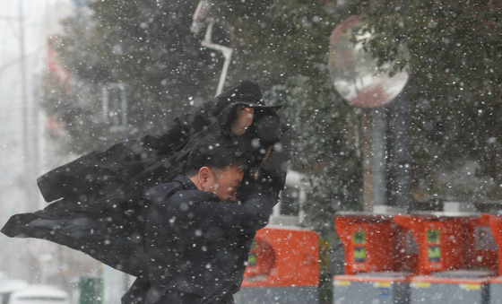 コートで吹雪に耐えながら歩く市民［写真　ニューシス］