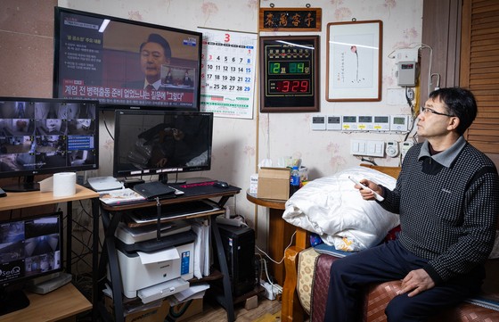 不景気に黙々と耐えてきた自営業者に非常戒厳は火に油を注ぐようなものだった。忠清南道天安でモーテルを運営するハム・ジャンスさんが先月４日、自身の事務室で憲法裁判所の大統領弾劾審判関連ニュースを見ている。チョン・ミンギュ記者