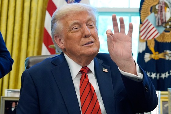 トランプ米大統領が１７日（現地時間）、ホワイトハウス執務室で行政命令に署名し、指でジェスチャーをしている。見方によっては「コイン」を意味するとも解釈される。　［ＡＰ＝聯合ニュース］