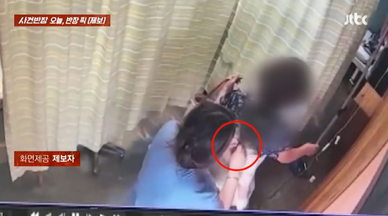 赤ちゃんの首にかかっていたネックレスを外す看護助務士。［ＪＴＢＣ『事件班長』　キャプチャー］ ​