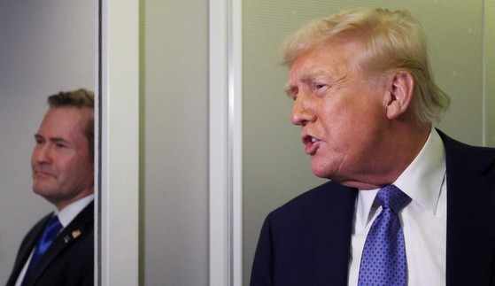 トランプ大統領が３月１６日、米ワシントンに帰国するエアフォースワンに乗り、当時のマイク・ウォルツ国家安全保障担当補佐官が見守る中で記者と話している。　［ロイター＝聯合ニュース］