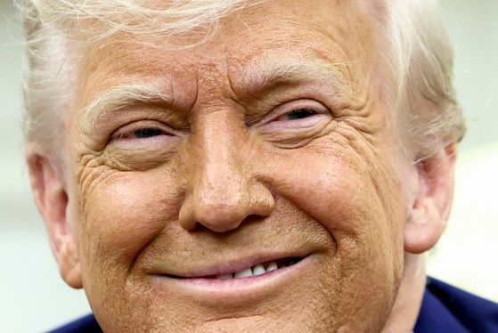 米国のドナルド・トランプ大統領が２１日（現地時間）、ホワイトハウス執務室で南アフリカのシリル・ラマポーザ大統領との首脳会談で、南アフリカで「白人農夫虐殺」が繰り返されているという疑惑を集中的に扱う中、笑顔を浮かべている。［写真　ロイター＝聯合ニュース］