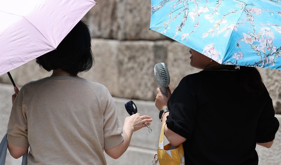 ２６日、ソウル清渓（チョンゲ）広場の市民たちが日傘などで暑さをしのいでいる。気象庁は当分、全国の昼の最高気温が２５度以上上がる初夏の天気が続くものと予報した。［写真　ニュース１］