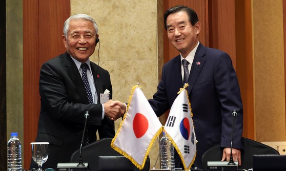 韓日経済協会の金鈗会長と日韓経済協会の麻生泰副会長が２８日午後にソウル市内のホテルで開かれた第５７回韓日経済人会議閉会式で共同声明採択に先立ち握手をしている。［写真　ニュース１］