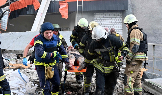 ウクライナのハルキウで救助隊員が負傷者を救助し搬送している。［写真　ＡＦＰ＝聯合ニュース］
