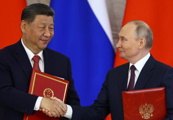 先月８日（現地時間）、ロシアのウラジーミル・プーチン大統領（右）と中国の習近平国家主席がロシア・モスクワのクレムリン宮（大統領府）で首脳会談後に「新時代における全面的な戦略協力パートナーシップ深化の声明」署名式で握手をしている。［写真　ロイター＝聯合ニュース］