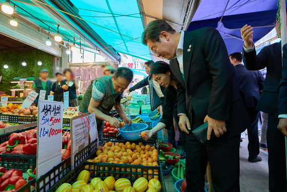 李在明大統領と金恵景夫人が６日にソウルの南城市場を訪問し果物を選んでいる。［写真　聯合ニュース］