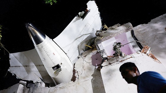 １２日（現地時間）、インド北西部のグジャラート州アーメダバードで墜落した飛行機のがれきの周りに人々が立っている。［写真　ＡＰ＝聯合ニュース］