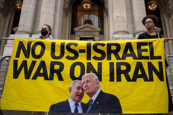 １８日（現地時間）、米ニューヨークで開かれた「イランとの戦争禁止」集会でデモ隊がドナルド・トランプ米大統領とイスラエルのネタニヤフ首相の写真が入った横断幕を持っている。［写真　ロイター＝聯合ニュース］