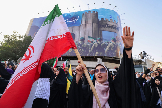 米国が爆撃機でイラン核施設を精密打撃した２１日、イランの首都テヘランで開かれた集会で女性がイランの国旗を持って米国に抗議している。　［ＡＦＰ＝聯合ニュース］