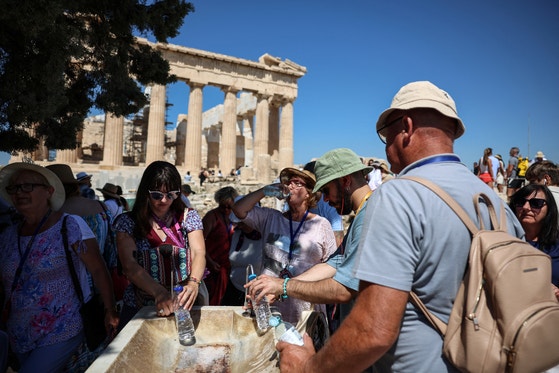 ７日（現地時間）、ギリシャの首都アテネの代表的な観光名所アクロポリスを訪れた観光客が、４０度を超える猛暑に水で暑さをしのいでいる。［写真　ロイター＝聯合ニュース］