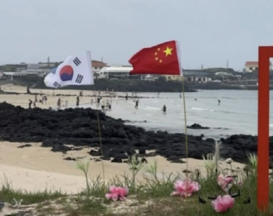 済州牛島のあるビーチに中国の国旗が太極旗と並んで立てられている様子。［Ｔｈｒｅａｄｓ　キャプチャー］