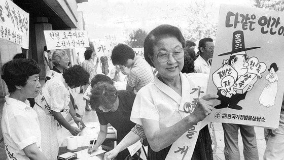 ２００５年の戸主制廃止は、韓国女性運動史において最大の転換点だった。１９８４年、李兌栄（イ・テヨン）弁護士（右）を中心とした家族法改正キャンペーン。「皆同じ人間」というポスターの言葉が見える。［中央フォト］