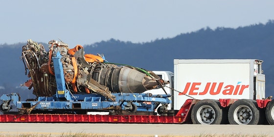 チェジュ航空旅客機の事故から７日目となる今年１月４日午後、全羅南道（チョルラナムド）に位置する務安（ムアン）国際空港の事故現場で、ローカライザー（方位角施設）の土台に衝突したチェジュ航空７Ｃ２２１６便のエンジンが積載されたトラックが移動している。［写真　ニュース１］