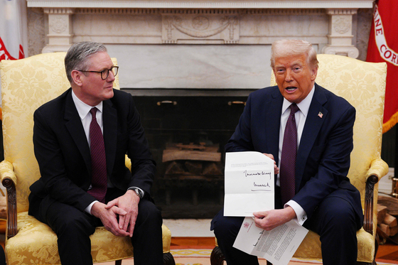 トランプ米大統領（右）が２月２７日にホワイトハウスでスターマー英首相から受け取った英国王チャールズ３世の国賓訪問招待状を見せている。［写真　ＡＦＰ＝聯合ニュース］